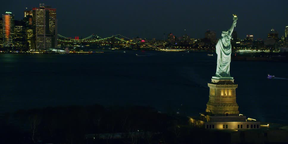 The statue of liberty illuminates in the night sky