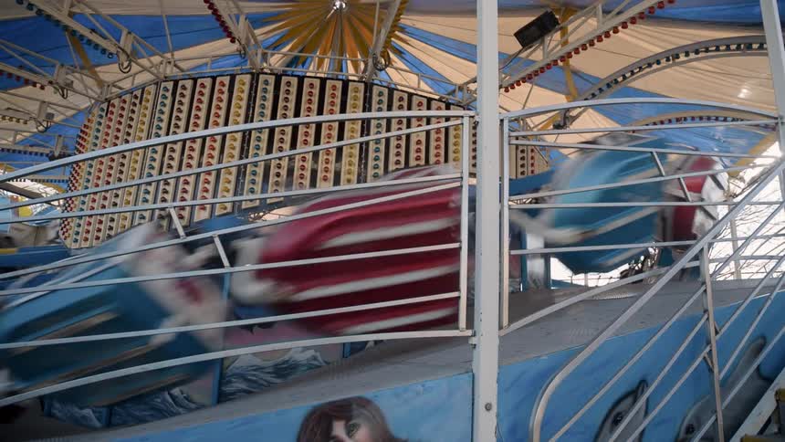 An empty carnival ride is running in circles on a track during the day