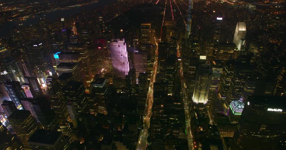 Busy city streets bordered with tall buildings at night