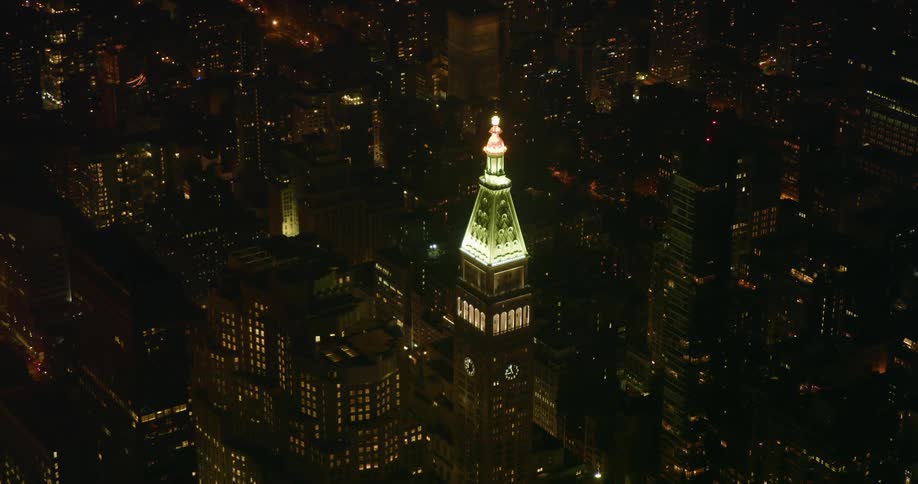 A tall city tower illuminates the night sky