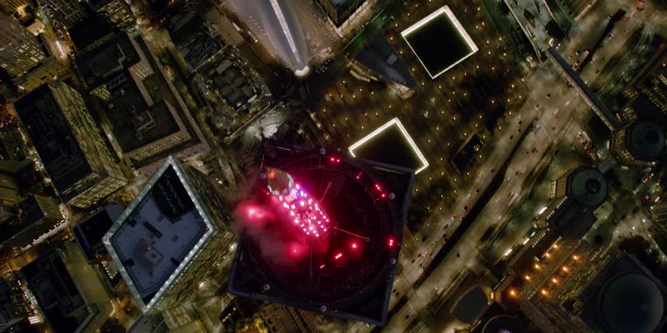 The top of a tall city building shines red lights into the night