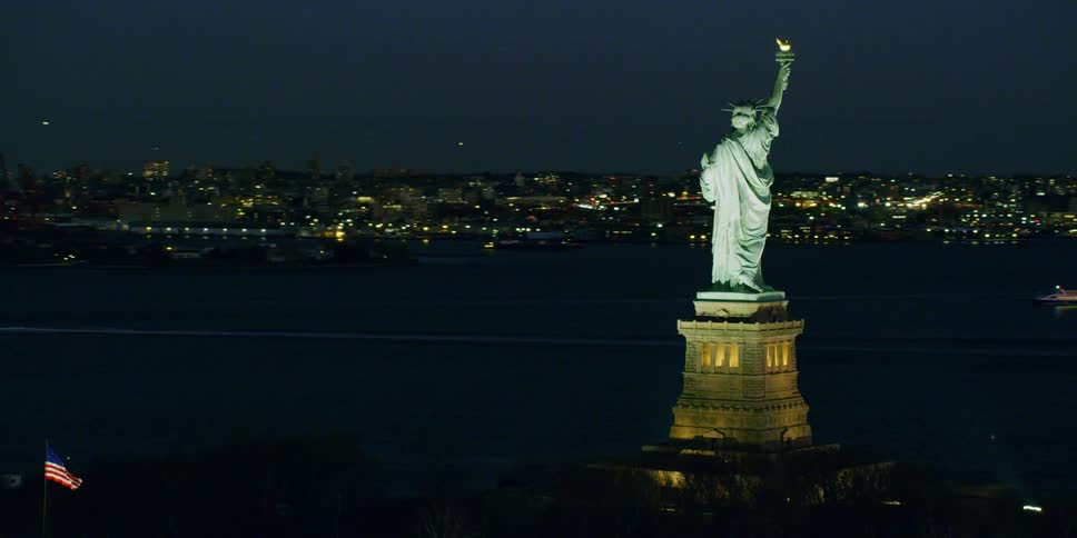 The statue of liberty illuminates in the night sky