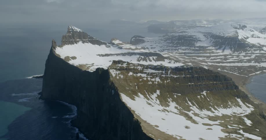 Snow and ice cover a mountain by the water