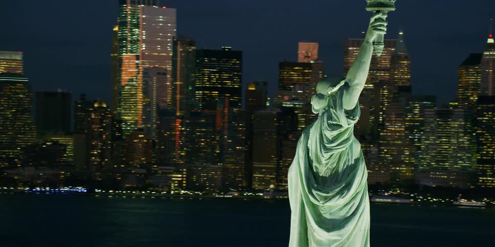 The statue of liberty illuminates in the night sky