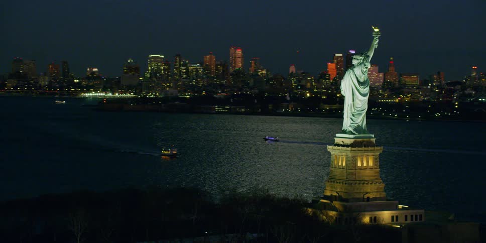 The statue of liberty illuminates in the night sky