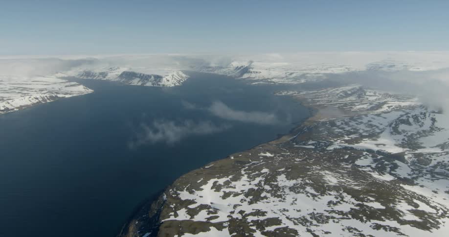Ice and snow cover the mountains near the water