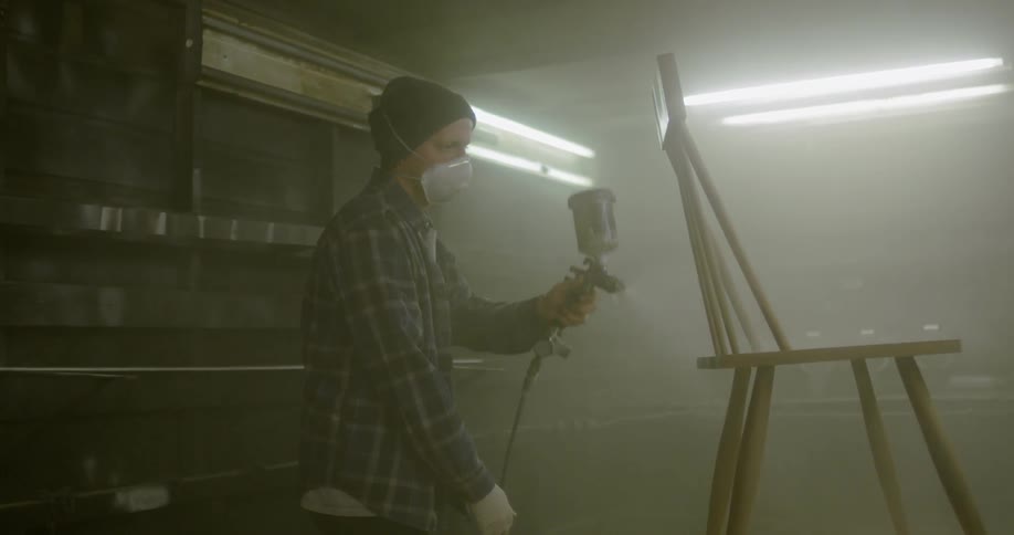 A person spray paints a wooden chair
