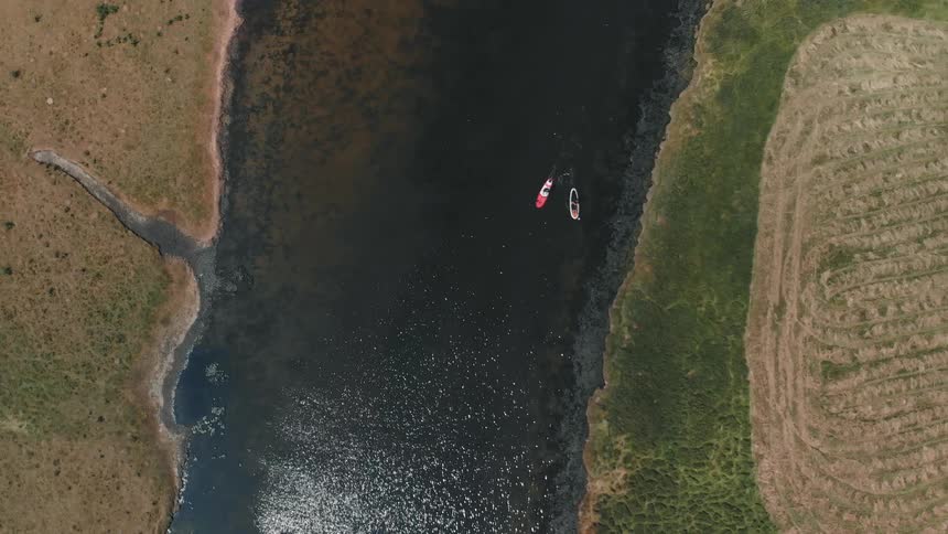 Two kayaks are paddling close together in a river during the day