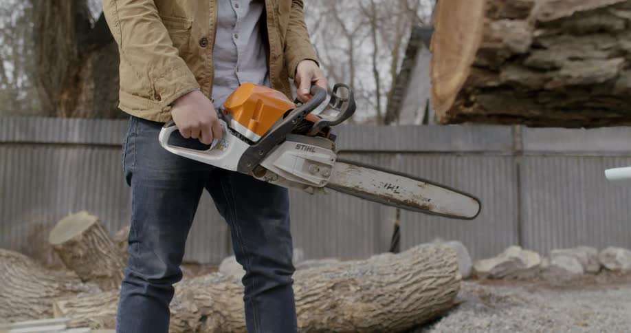 A man is using a chainsaw to cut a tree