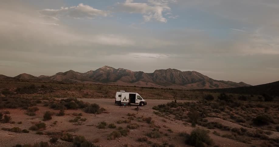 A van is parked by tall desert mountains
