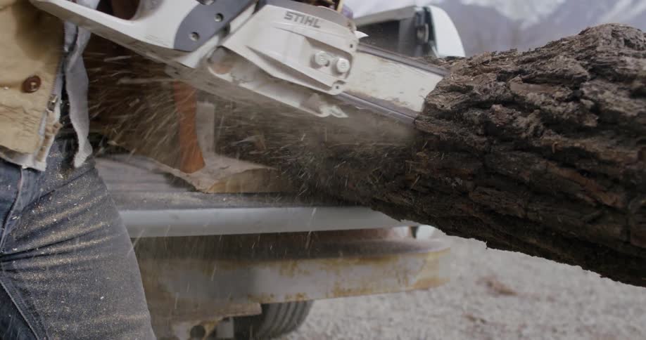 A man cuts a tree trunk with a chainsaw