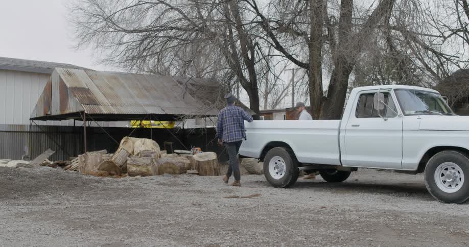 Men exit an old pickup truck and walk around back