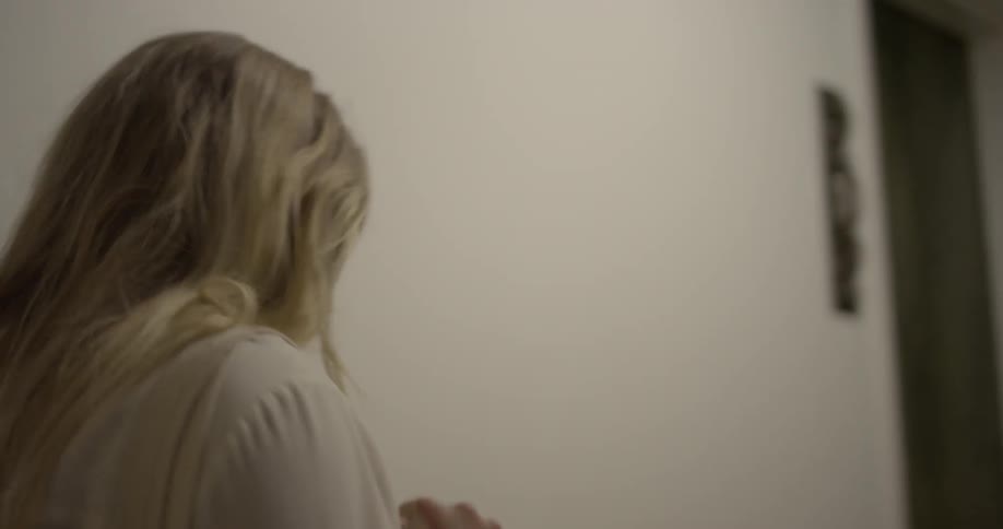 A woman flips her hair to the side as she walks in a hallway