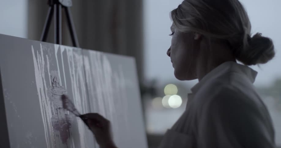 A woman paints on a canvas on an easel