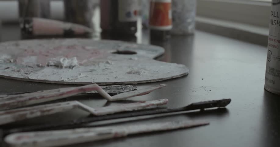 Art palette lying on a table with utensils and paints on both sides