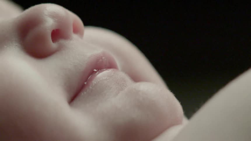 A baby smiles and forms drool bubbles
