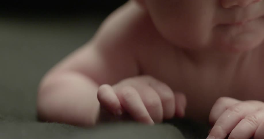 A baby on his belly wiggles his fingers