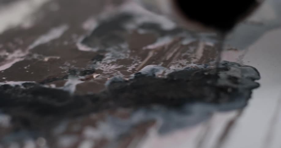 An artist pours paint on a canvas