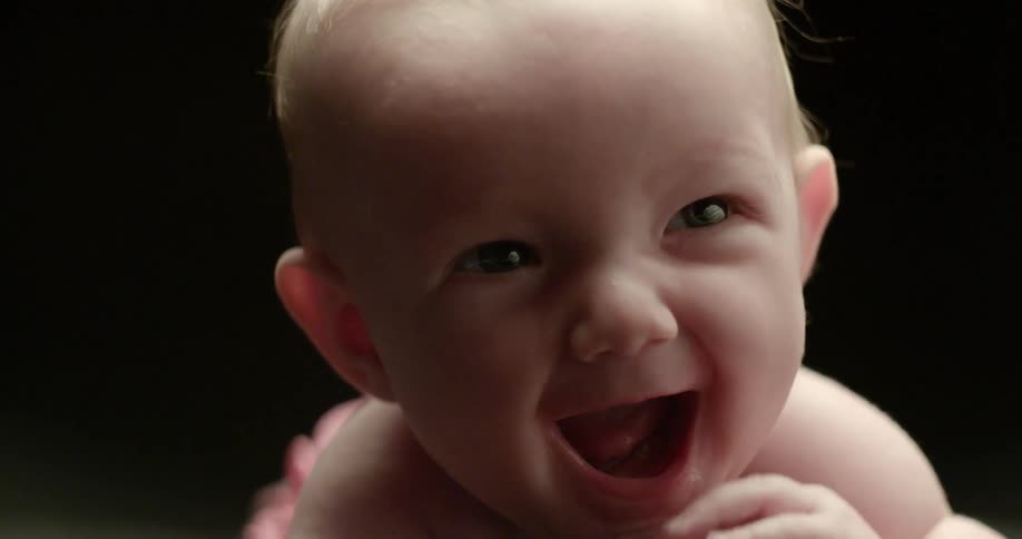 An infant smiles in a black room