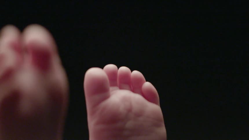 An infant fidgets and feels his feet