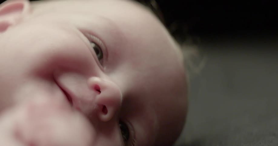 An infant is laying down and smiling