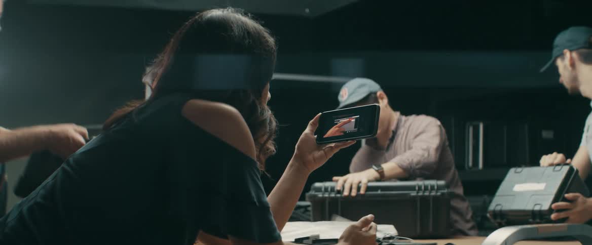 Woman watches video on smartphone while men pack cases
