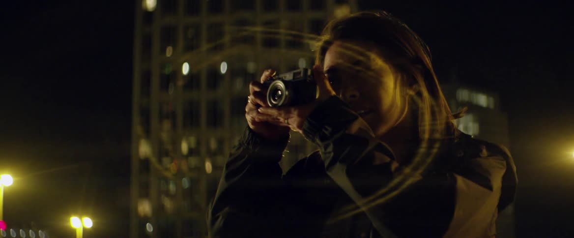 A woman takes a photograph outside at night