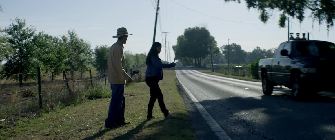 Man and woman hitchhike on a rural road
