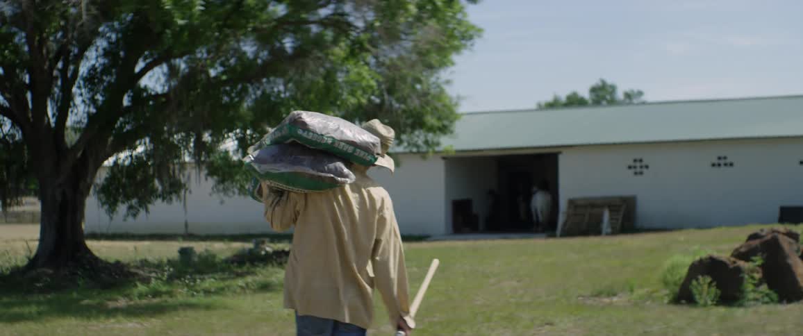 A man is carrying mulch into a barn