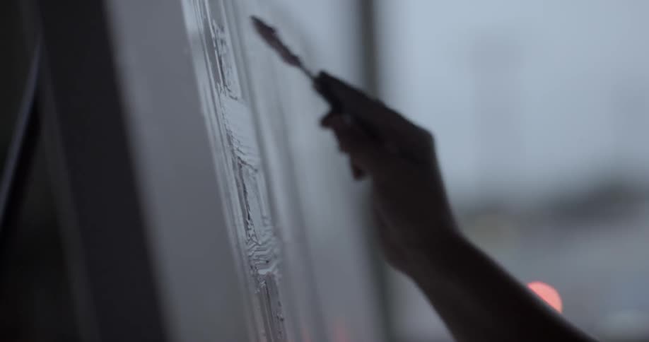 An artist is painting a picture in a studio at dusk