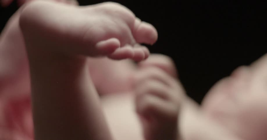 An infant squirms and kicks his feet