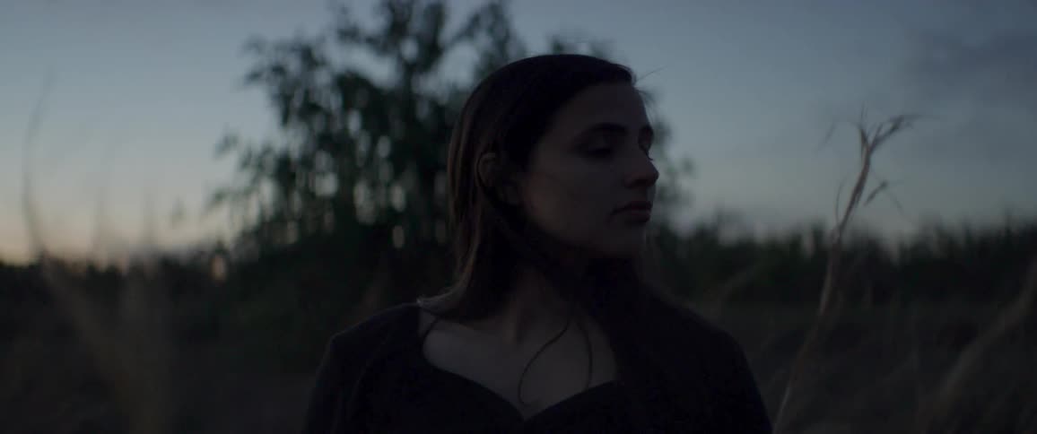 A young woman stands outside and looks around