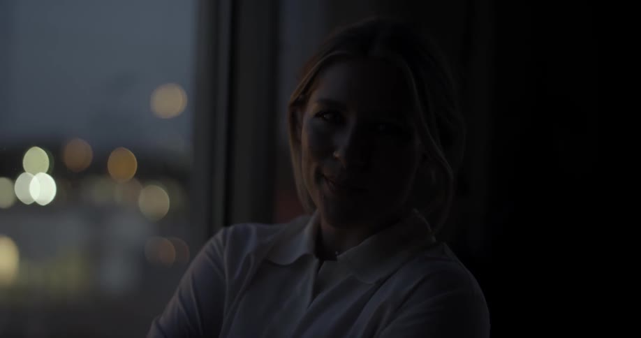 A woman smiles by an apartment window