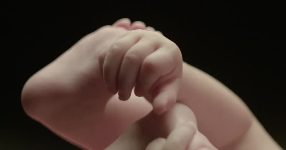 A baby reaches and plays with its feet