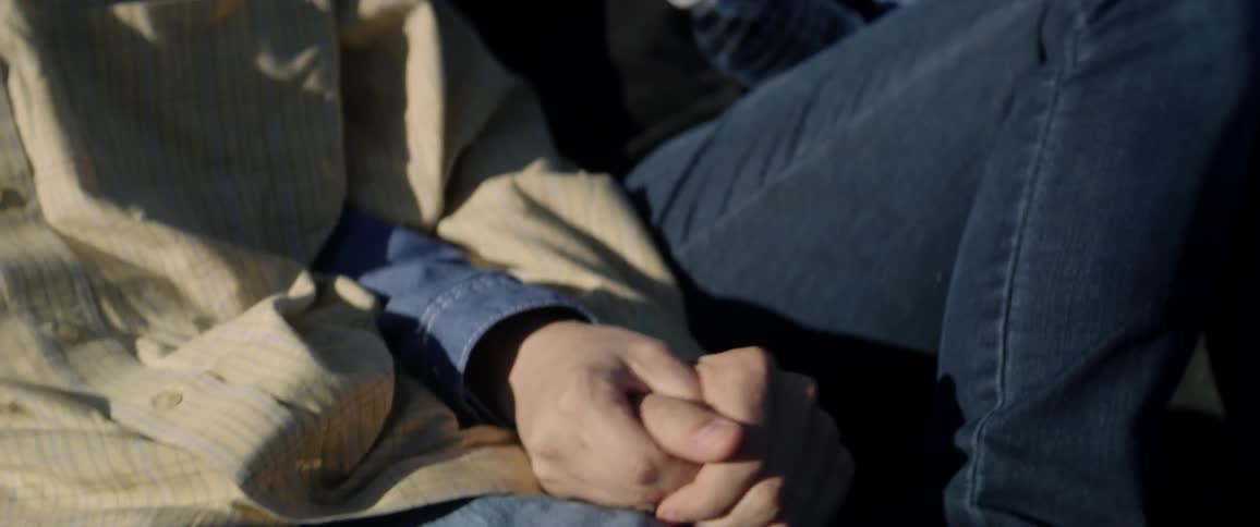 A man and woman hold hands in the back of a truck