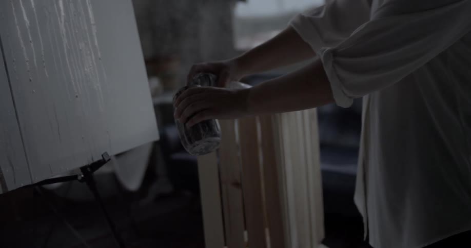 A woman sprays paint into a jar