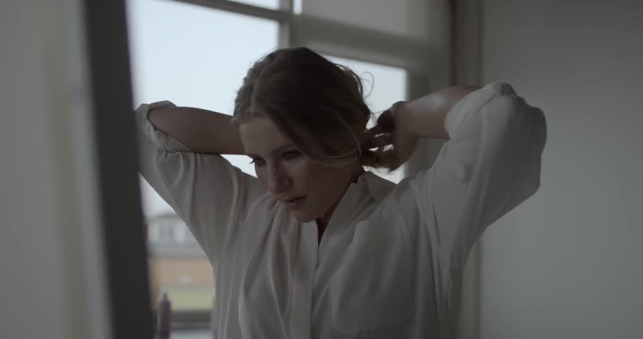 A woman smiles and ties her hair back