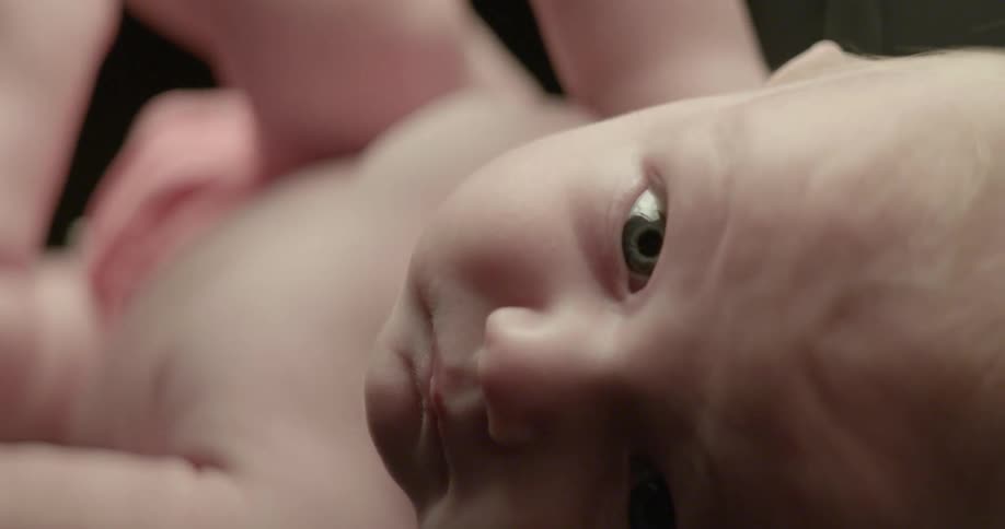 An infant rolls around in a black room