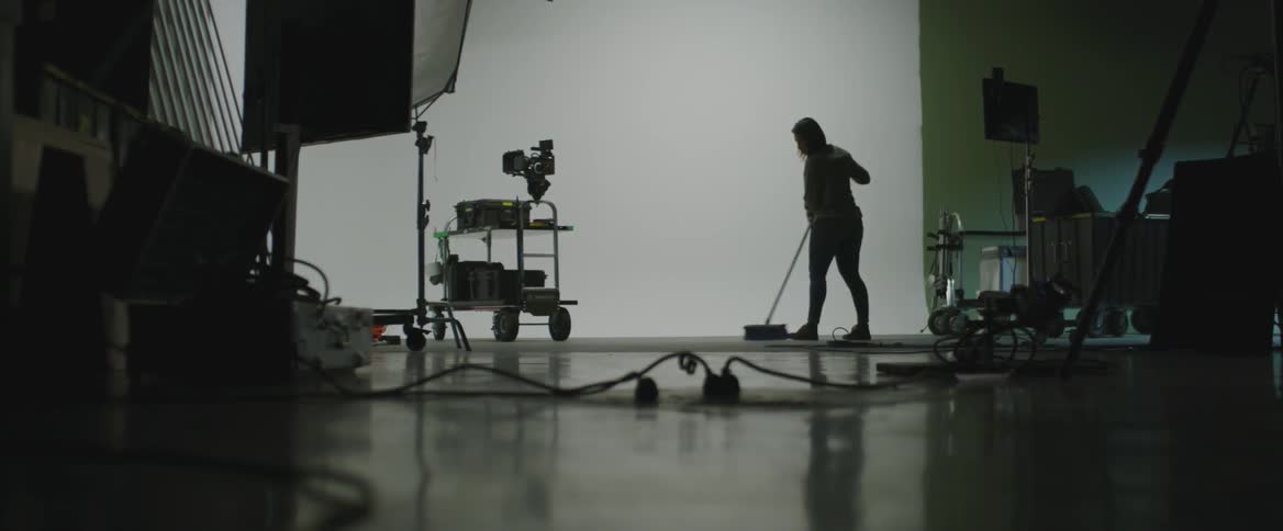 A woman is sweeping the area in front of a screen in a film studio
