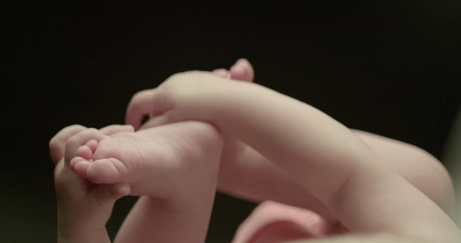 A baby is playing with its feet
