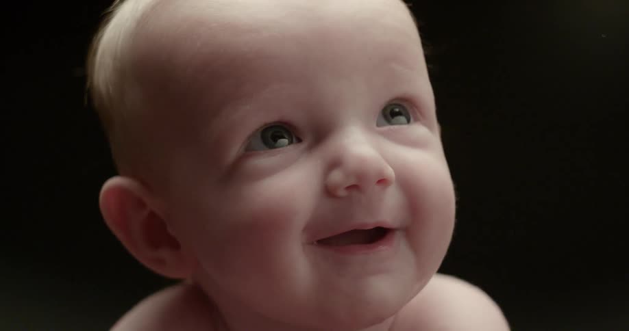 An infant looks up and smiles
