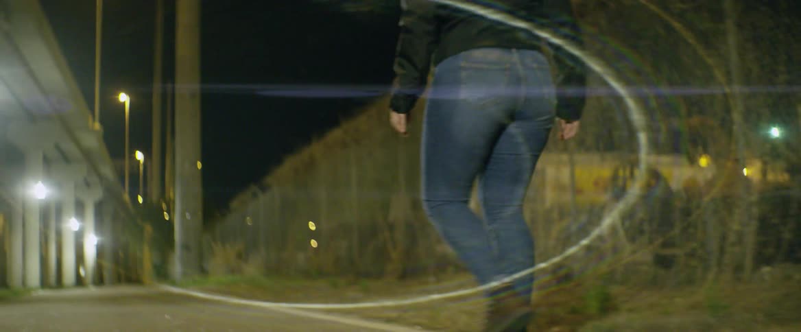 A woman is riding a skateboard in an urban area at night