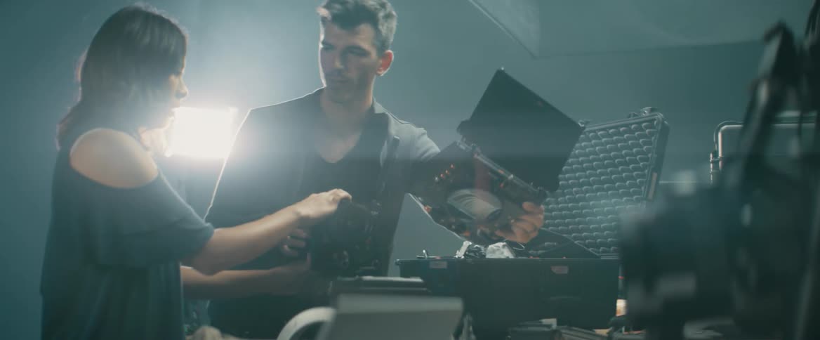 A man assists a woman to assemble a camera
