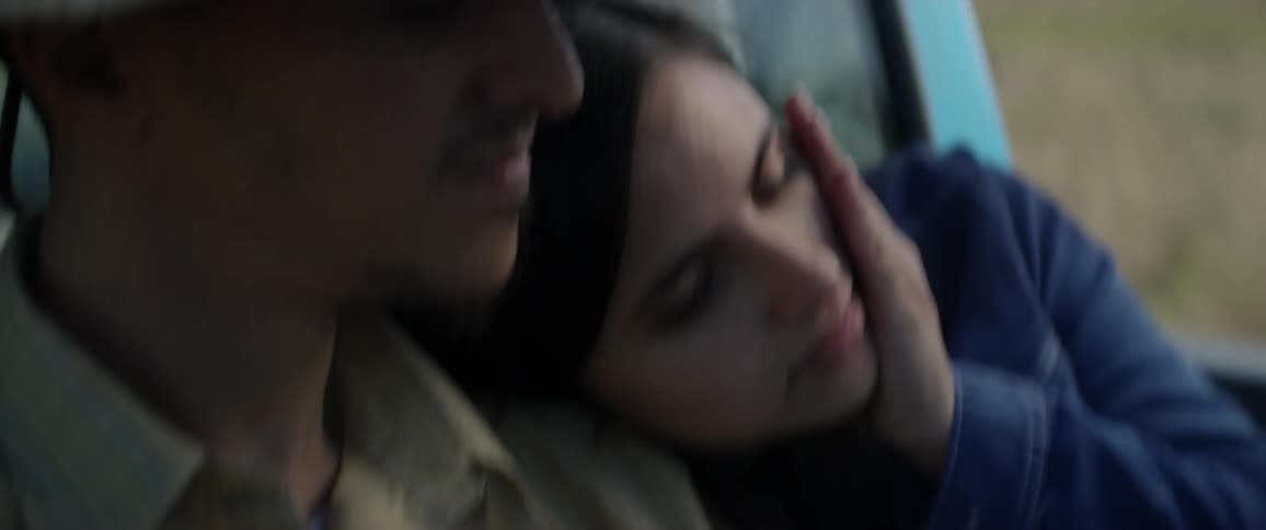 Couple riding in the back of a pickup as the woman leans on the man's shoulder