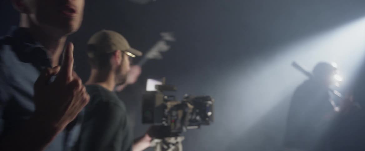 A man in a studio holds a baseball bat in front of a camera