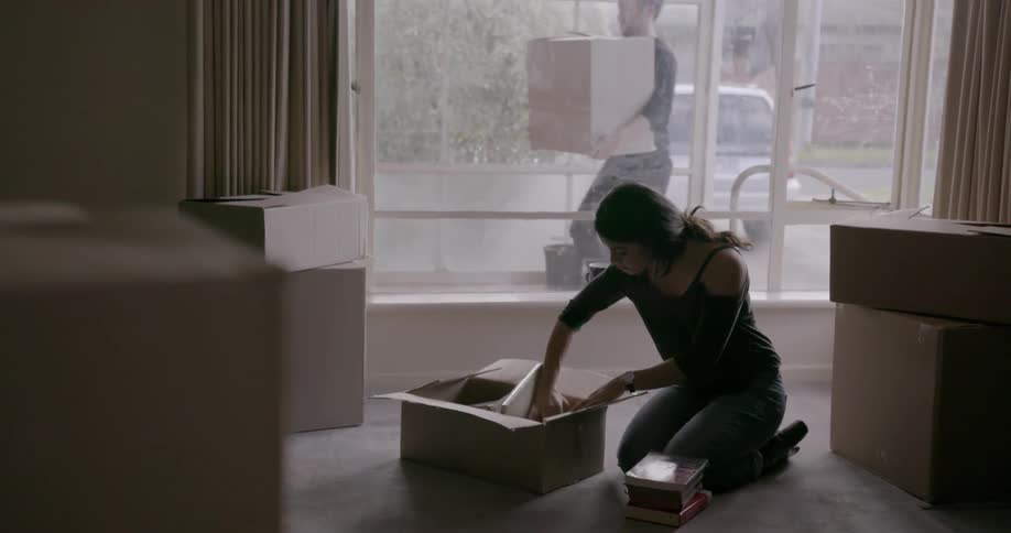 Woman kneels while unpacking a cardboard box