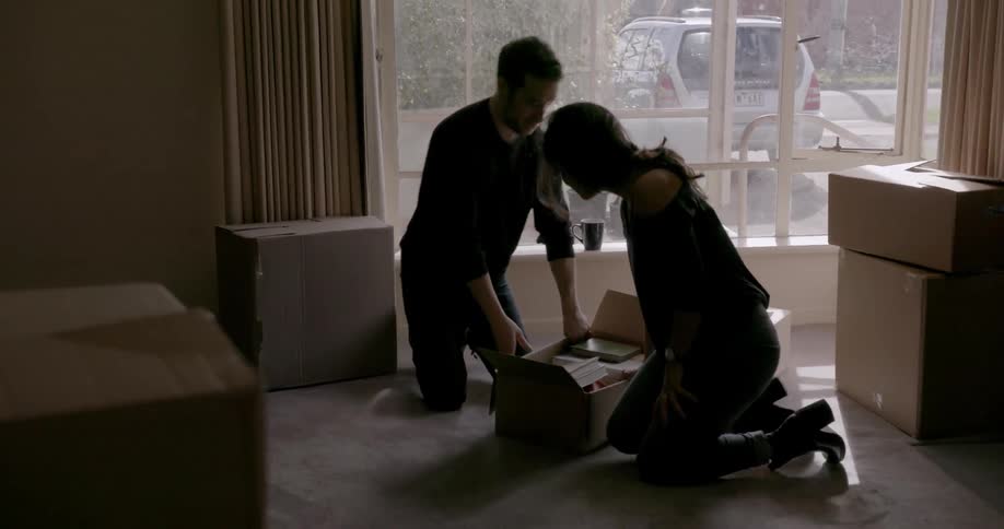 A man and woman unpack boxes in an apartment