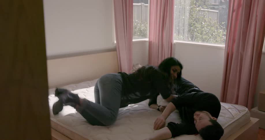 A man and woman plop down on a bed