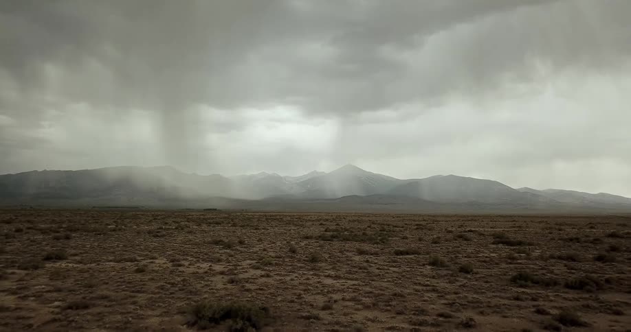 A storm rages by mountains in the desert