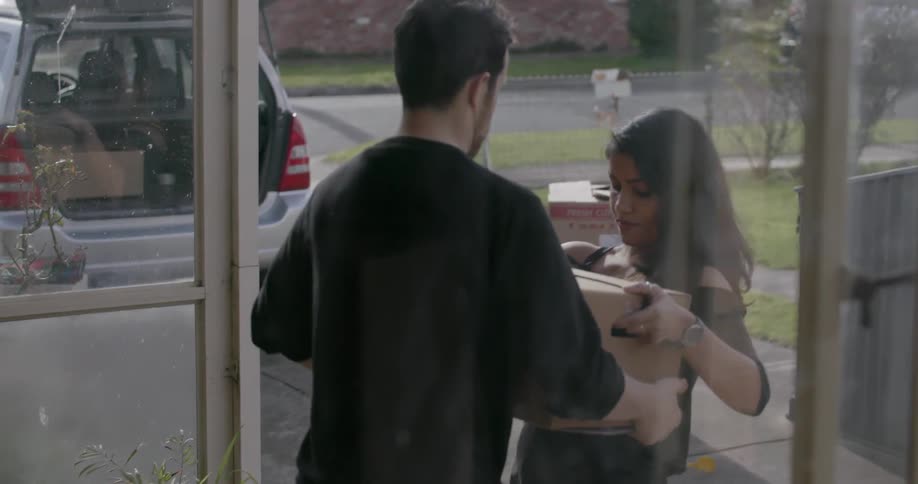 A man and woman unload boxes from a car